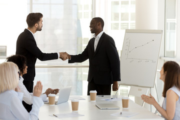 Diverse businessmen standing in office and shaking hands