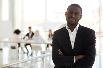 Black businessman standing in office with hands crossed on chest