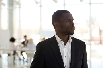 African businessman standing in office thinking looking away