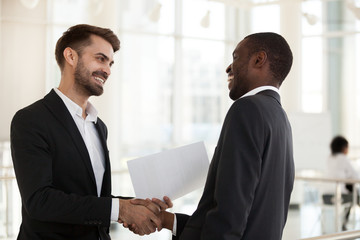 Positive diverse businessmen shaking hands before negotiating