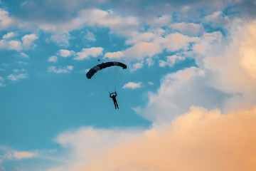 Parachutist falling from the sky in evening sunset dramatic sky. Recreational sport, Paratrooper silhouette on colored sky.