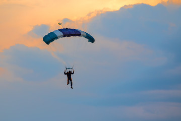 Parachutist falling from the sky in evening sunset dramatic sky. Recreational sport, Paratrooper...