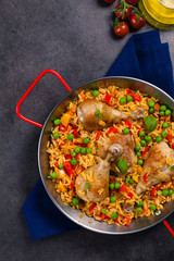 Arroz con pollo. Baked pieces of chicken with bone, rice with paprika and peas.