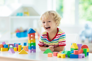 Kids toys. Child building tower of toy blocks. - obrazy, fototapety, plakaty