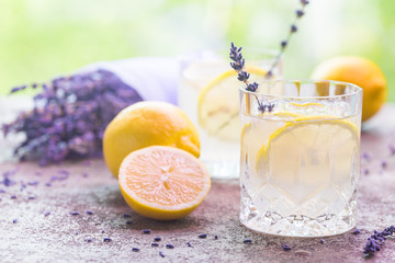 Lemonade with lemons and lavender on stone table over nature background
