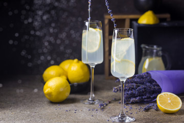 Lemonade with lemons and lavender on black stone table.