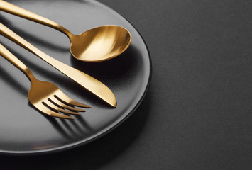 Gold cutlery set on black background