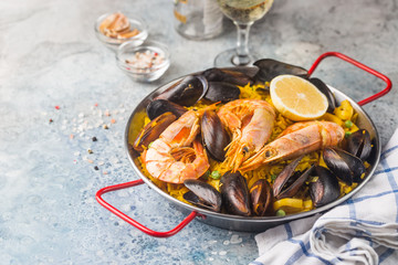 Traditional spanish seafood paella in a fry pan with white wine