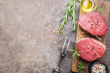 Raw marbled meat steak Filet Mignon with seasonings over stone background, top view.