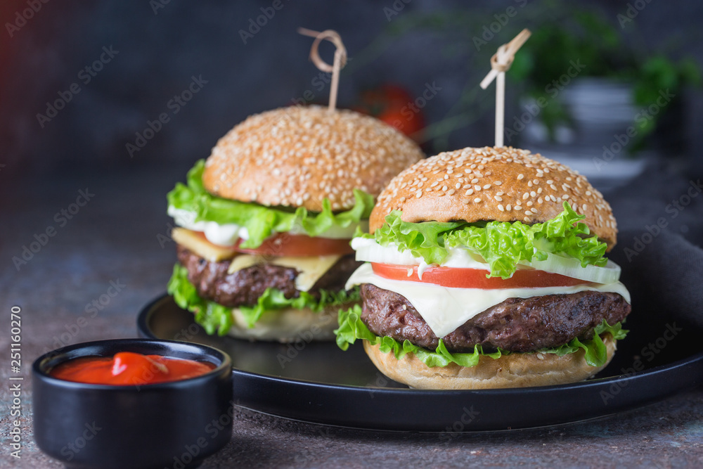 Wall mural hamburger with beef meat burger and fresh vegetables on dark background. tasty fast food.