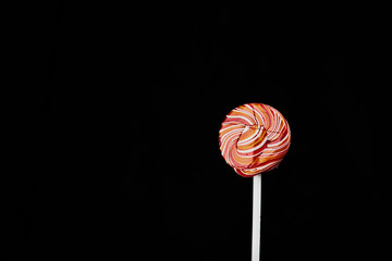 red, round colored Lollipop on black background