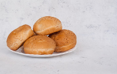 Buns with sesame seeds for hamburger on a plate. Free space for text. Copy space.