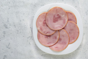 Slices of ham for Breakfast are beautifully laid out on a white plate. The view from the top. Copy space.