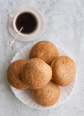 Muffins with sesame seeds for Breakfast on a plate and a Cup of coffee. Free space for text. Copy space.