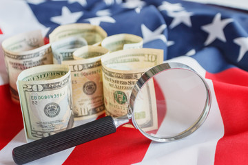 Magnifying glass and American dollars on the national flag of United States of America, background
