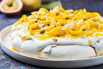 Meringue cake Pavlova with fresh mango and passion fruit and whipped cream on slate, stone or...