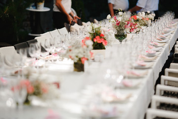Bouquets of flowers and crystal dishes decorated on a white table.