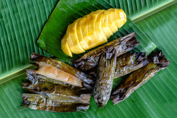 Thai style dessert, yellow mango with banana sticky rice in palm leaves. Yellow mango and sticky rice is popular traditional dessert of Thailand.