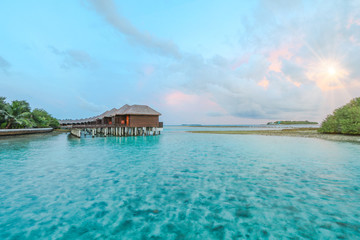 Amazing island in the Maldives ,water villa ,wooden bridge and beautiful turquoise waters with sunrise background for holiday ,summer, vacation .