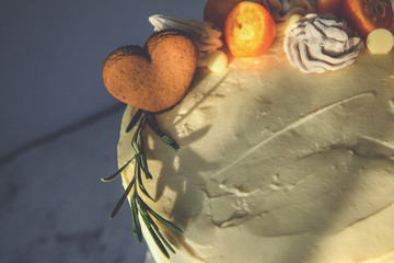 White cake, decorated with ginger cookies, marshmallows, on a dark background