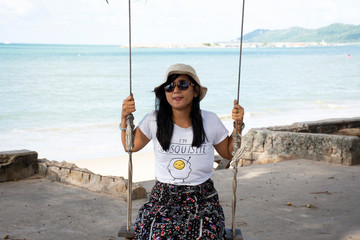 Thai women sit relax and playing swings toy at Ban Pae beach in Rayong, Thailand