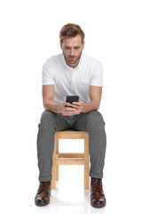 casual man reading on his phone while sitting