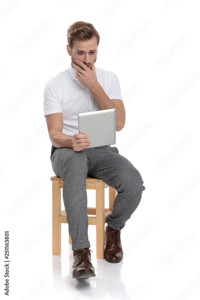 Wall mural shocked seated man reads something on his tablet