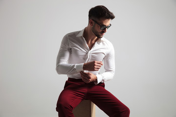 attractive man wearing glasses buttoning up his shirt sleeve