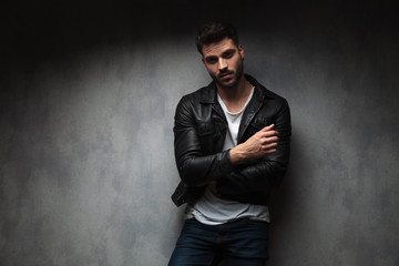 smiling young fashion man standing with hands crossed