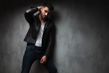 fashion man in leather jacket posing with hand behind  head