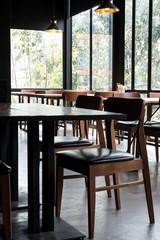 Table and chair set in modern cafe minimalistic interior design with big window and hanging ceiling lamps