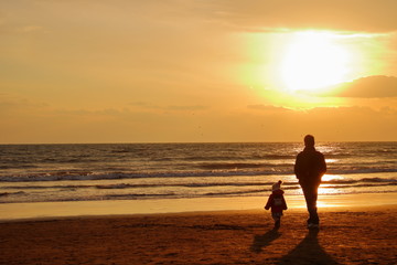 湘南海岸の夕日を眺める親子連れ