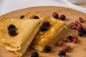 Pancakes on a wooden board with honey, jam and berries