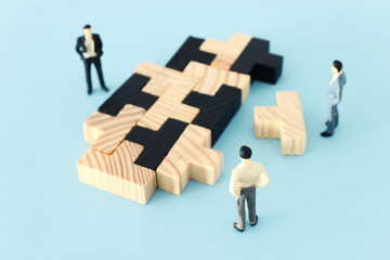 puzzle blocks with miniature people over wooden table ,human resources, problem solving and management concept