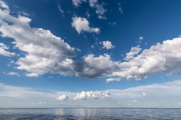 Naklejka na ściany i meble White clouds in the blue sky above the water