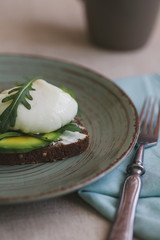 sandwich with avocado, poached egg, arugula and cherry tomatoes