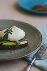 sandwich with avocado, poached egg, arugula and cherry tomatoes