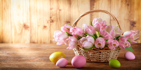 Easter holiday basket with beautiful pink tulips and Easter eggs.