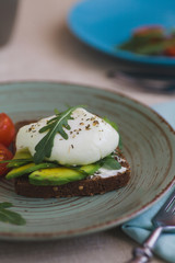 sandwich with avocado, poached egg, arugula and cherry tomatoes