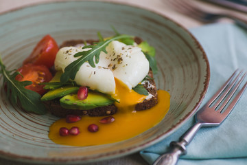 sandwich with avocado, poached egg, arugula and cherry tomatoes