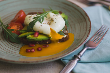 sandwich with avocado, poached egg, arugula and cherry tomatoes