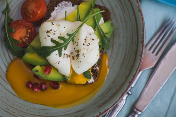 sandwich with avocado, poached egg, arugula and cherry tomatoes