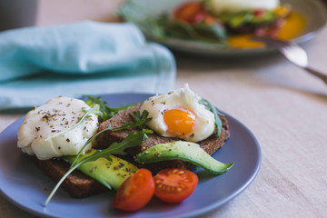 sandwich with avocado, poached egg, arugula and cherry tomatoes