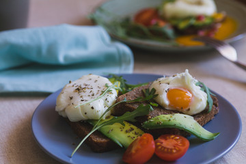 sandwich with avocado, poached egg, arugula and cherry tomatoes