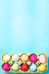 Easter eggs are painted in bright colors, lie in a cardboard eco-packaging. Blue background. Easter ideas. Space for text. Egg eco tray. Happy easter.