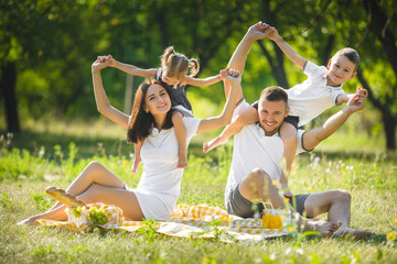 Young family having picnic outdoor. Mother, father and their kids having fun in the park. Summer resting at the nature.