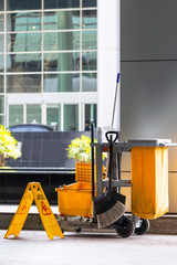 Janitorial and mop bucket on cleaning with caution wet floor sign.
