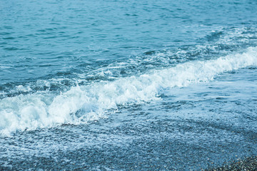 Beautiful foam waves on a sunny day in the Aegean Sea on the island of Evia in Greece