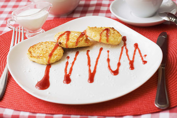 Cottage cheese pancakes with berry sauce for breakfast on red tablecloth