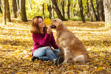 Beautiful woman with a golden retriever dog in autumn park